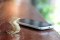 Coins with smart phone place on wooden floor. Royalty Free Stock Photo