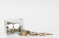 Coins spilled from glass jar, with copy space on white background Royalty Free Stock Photo