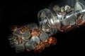 Coins spilled from a mason jar on black background Royalty Free Stock Photo