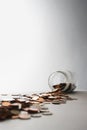 Coins spilling out of jar on its side in studio