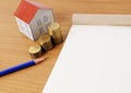 Coins stack with blue pencil and paper house and notepaad