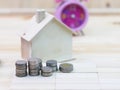 coins stack, clock and house is located on a wooden floor on sav