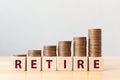 Coins on stack stair as step growing growth and wooden cube block with word RETIRE. Money pension retirement concept Royalty Free Stock Photo