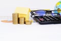 Coins stack and yellow paper house and Eyeglasses and calculator on business chart document Royalty Free Stock Photo