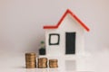 Coins stacked with a blurred house on the background: real estate, property investment, house mortgage, savings concept. Royalty Free Stock Photo