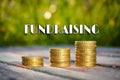 Coins stacked with Fundraising text on natural background.