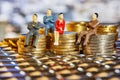 The coins are stacked on top of each other with the figures of business people sitting on them, a market crisis and a fragile Royalty Free Stock Photo