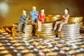 The coins are stacked on top of each other with the figures of business people sitting on them, a market crisis and a fragile Royalty Free Stock Photo