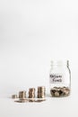 Coins stacked up next to a half empty jar with coins in and with a label on saying pension fund. Pension, financial, savings, Royalty Free Stock Photo