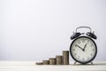 Coins stacking with alarm clock on wooden table , time and money management concept Royalty Free Stock Photo