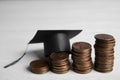 Coins and student graduation hat on white background. Tuition fees concept Royalty Free Stock Photo