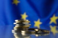 Coins on table against European Union flag, closeup. Space for text Royalty Free Stock Photo