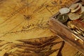 The coins are yellow in a wooden antique chest on an old world map. Royalty Free Stock Photo