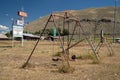 Swingset and playground at an old abandoned seedy motel, with overgrown weeds in the parking