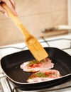 Cokk's hand preparing a spiced pork chop in the frying pan Royalty Free Stock Photo