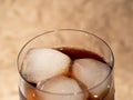 Cola with ice in a glass. Carbonated refreshing drink with ice. Cola bubbles.