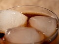 Cola with ice in a glass. Carbonated refreshing drink with ice. Cola bubbles.