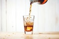 cola pouring over ice cubes in a glass cup