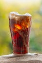 Cola water pouring into glass with ice cubes on sand Royalty Free Stock Photo