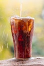 Cola water pouring into glass with ice cubes on sand Royalty Free Stock Photo