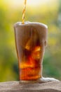 Cola water pouring into glass with ice cubes on sand Royalty Free Stock Photo