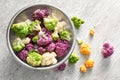Colander with colorful cauliflowers on light table Royalty Free Stock Photo