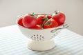 Colander with delicious tomatoes on table