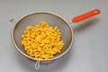 colander with a red handle in which pasta is in the form of a spiral Royalty Free Stock Photo