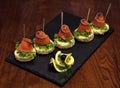 Cold appetizers, canape with red fish, wooden background. Canape with salad leaves, red fish, lemon and dill. Delicious