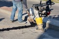 A road worker shovels cold asphalt to seal the seam on the road