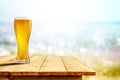 Cold beer in big glass on wooden table with sand and beach background Royalty Free Stock Photo