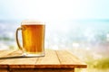 Cold beer in big glass on wooden table with sand and beach background Royalty Free Stock Photo