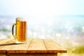 Cold beer in big glass on wooden table with sand and beach background Royalty Free Stock Photo