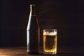 Cold beer bottle and glass with fresh beer in drops of water on dark background, craft brewery Royalty Free Stock Photo