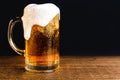 Cold beer with foam in a mug, on a wooden table and a dark background with blank space for a logo or text. Stock Photo mug of cold Royalty Free Stock Photo
