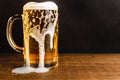 Cold beer with foam in a mug, on a wooden table and a dark background with blank space for a logo or text. Stock Photo mug of cold Royalty Free Stock Photo