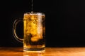 Cold beer with foam in a mug, on a wooden table and a dark background with blank space for a logo or text. Stock Photo mug of cold Royalty Free Stock Photo