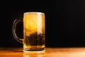 Cold beer with foam in a mug, on a wooden table and a dark background with blank space for a logo or text. Stock Photo mug of cold Royalty Free Stock Photo