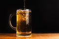 Cold beer with foam in a mug, on a wooden table and a dark background with blank space for a logo or text. Stock Photo mug of cold Royalty Free Stock Photo