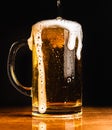 Cold beer with foam in a mug, on a wooden table and a dark background with blank space for a logo or text. Stock Photo mug of cold Royalty Free Stock Photo