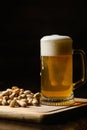 Cold beer with foam in a mug, on a wooden table and a dark background Royalty Free Stock Photo