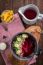 Cold beetroot soup with eggs, baked potatoes, souce, rustic wooden background, white jug, pink tablecloth, top view Royalty Free Stock Photo