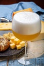 Cold belgian beer in glass served in cafe with variety of hard cheeses, tasty european food Royalty Free Stock Photo