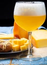 Cold belgian beer in glass served in cafe with variety of hard cheeses, tasty european food Royalty Free Stock Photo