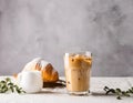 Cold black coffee with ice cubes in tall glass and fresh croissant. Refreshing coffee drink on a table gray background Royalty Free Stock Photo