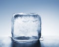 Cold blue ice block melting into water puddle