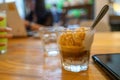 Cold Brew Iced Coffee Affogato, Vanilla Ice-Cream in a glass next to smart phone on wooden table and customers using laptop for Royalty Free Stock Photo