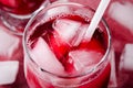 Cold cherry drink with ice cubes and cocktail tubes in glasses, on pink background Royalty Free Stock Photo