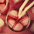 Cold cherry drink with ice cubes and cocktail tubes in glasses, on pink background Royalty Free Stock Photo