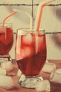 Cold cherry drink with ice cubes and cocktail tubes in glasses, on pink background Royalty Free Stock Photo